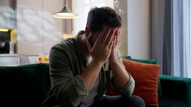 Depressed upset frustrated desperate Caucasian business man male guy homeowner businessman customer sitting couch holding head hands gesture trouble problems depression mental crisis burnout at home
