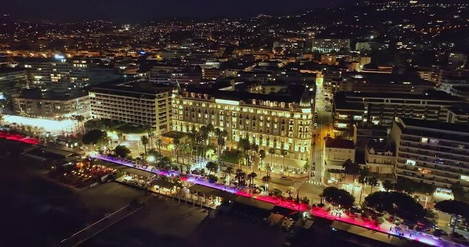 Aerial video in Cannes with a view of the beach and luxurious buildings at Night. Prestigious nightlife in Cannes. Cannes renowned for best colorful venues at night on the Cote Azur, French Riviera