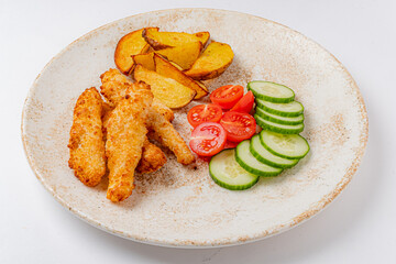 Enjoy a delicious platter featuring crunchy chicken strips, roasted potatoes, and vibrant veggies