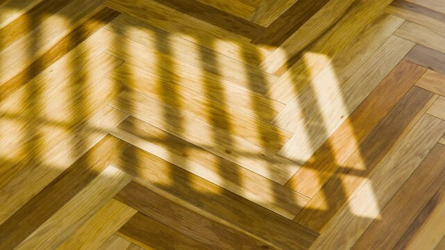 Natural light creates moving shadows of a window on a herringbone parquet floor