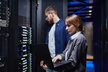 IT professionals in a data center managing server operations while collaborating on tasks with...