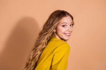 Fototapeta premium Beautiful young woman with wavy blond hair smiling against a beige background in stylish fashion