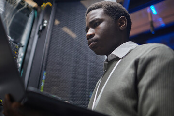 Skilled technician working diligently in a server room analyzing system data on screen ensuring network stability and security