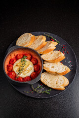 Delicious baked cheese nestled in a sauce of roasted tomatoes and served with crusty bread