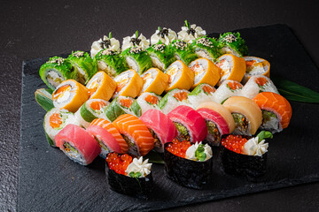 A colorful array of fresh sushi rolls beautifully displayed on dark slate