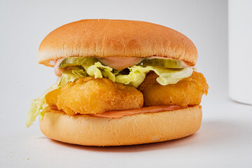 Crispy fish fillets are nestled between layers of fresh lettuce and tangy pickles on a soft bun
