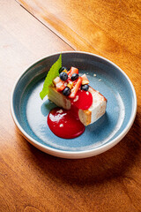 Savoring a decadent cheesecake slice adorned with vibrant berry sauce and fresh fruit