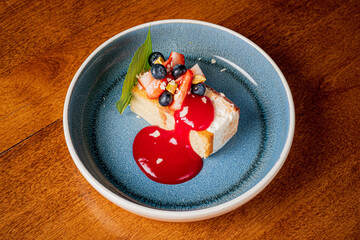 A creamy dessert topped with strawberries and blueberries, elegantly presented