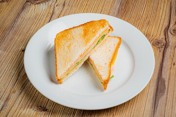 A perfectly toasted sandwich, cut in half, showcases fresh ingredients on a clean white plate