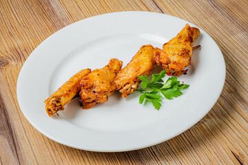 Savory chicken wings displayed neatly on a white plate, accompanied by vibrant green herbs