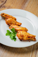 Crispy chicken wings arranged neatly on a plate, garnished with vibrant green herbs, ready to enjoy