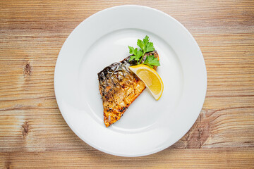 Tasty grilled fish fillet served with a slice of lemon and fresh parsley on an elegant plate