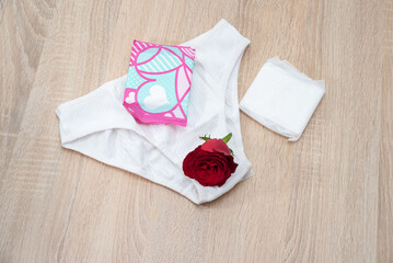 Pads and tampons, underwear, rose flower as a symbol of menstruation. Menstrual cycle. Hygiene and prostatitis