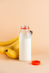 Korean banana milk in a plastic bottle with bananas on a beige background. Traditional Korean drink. Vertical orientation.