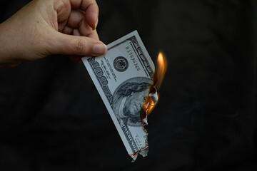 A hand holding a banknote is burning