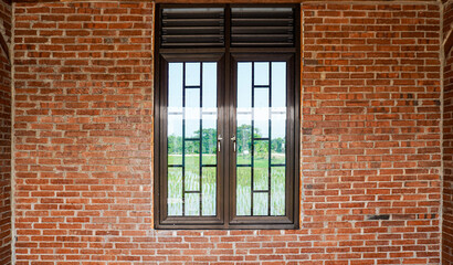 A window with metal bars set against a brick wall, offering a glimpse of the outside landscape...