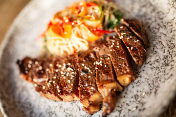 Sliced grilled steak with sesame seeds and colourful asian noodle salad, close up shot with...