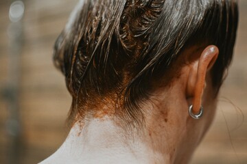 Close-up of dyed red female hair in a bun on a brown background