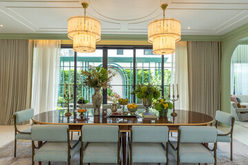 Beautiful luxurious traditional style dining room with bouquets of flowers on the table. Elegance dinning table with luxurious pendant.