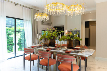 Beautiful luxurious traditional style modern dining room with bouquets of flowers on the table. Elegance dinning table with luxurious pendant.