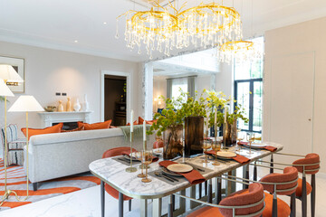 Beautiful luxurious traditional style modern dining room with bouquets of flowers on the table. Elegance dinning table with luxurious pendant.