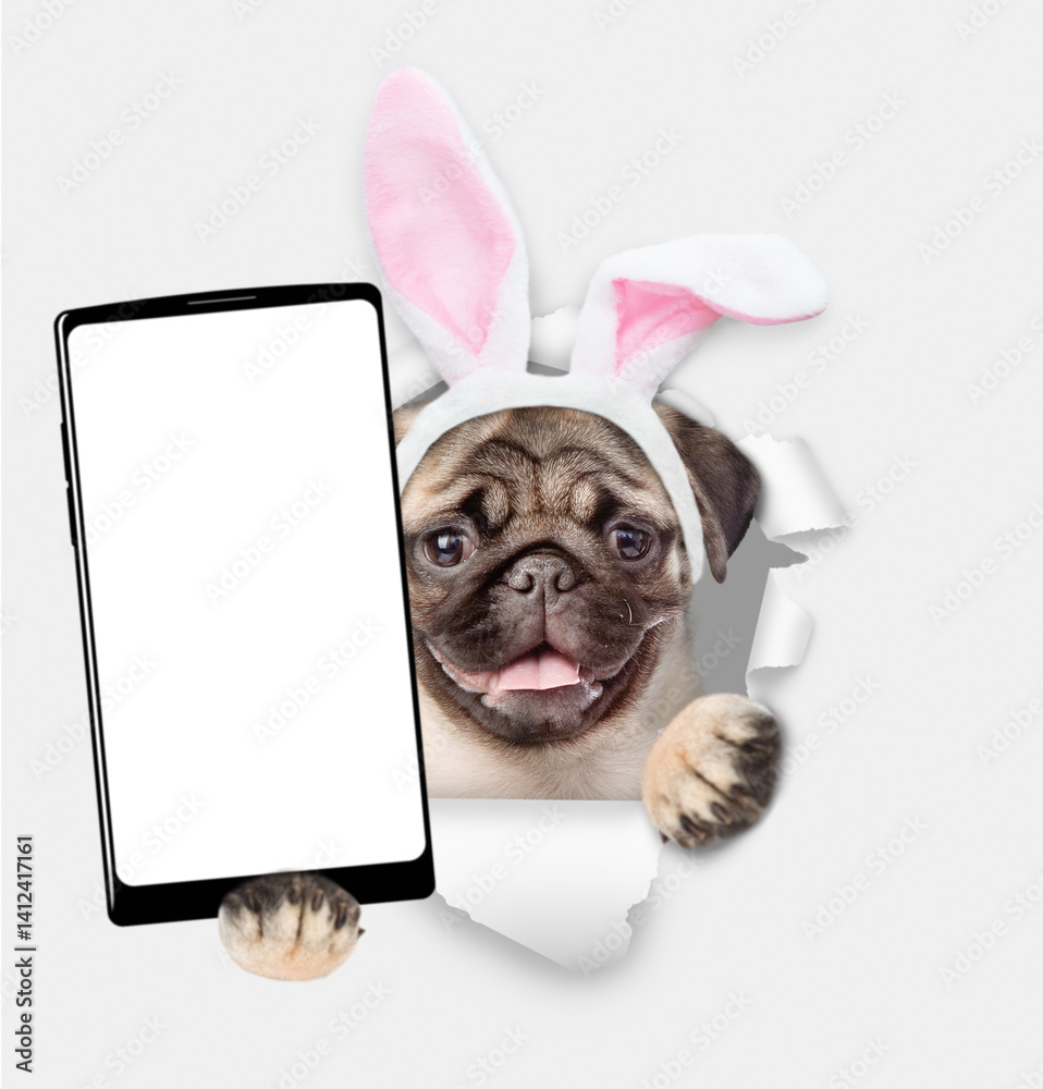 Aufkleber happy mastiff puppy wearing easter rabbits ears holds big smartphone with white blank screen through
