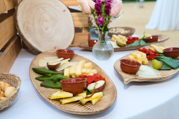 Different types of cheese on wooden trays to serve at an event. Decoration with flowers and wooden boxes.