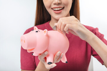 Beautiful woman saving money in a piggy bank, female putting money coin into piggy, investment financial concept.