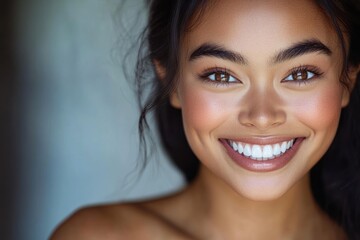 Obraz premium Smiling woman with dark hair and brown eyes portrait against a light background.