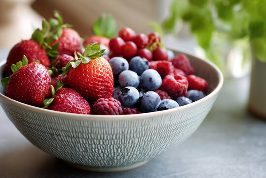 close-up of a textured ceramic bowl filled with fresh berries in morning light.