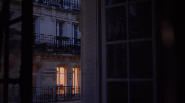 Warm light emanating from parisian apartment window at dusk