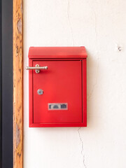 Bright Red Mailbox Mounted on a Plain Wall with Wood Trim Detail