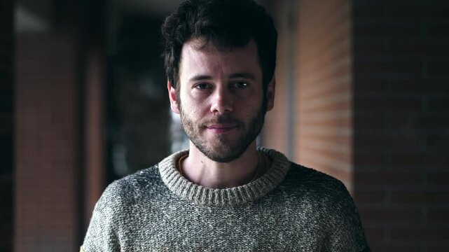 A bearded young man looks straight into the camera with serious intensity, silently confronting something unresolved or challenging in his life