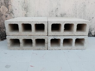 Four concrete blocks stacked in two rows, placed outdoors against a weathered wall, construction and industrial scene.