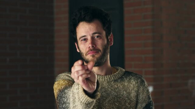 Vertical: A young man uses his fingers to indicate something very small, subtly mocking how unimportant or disappointing the situation is