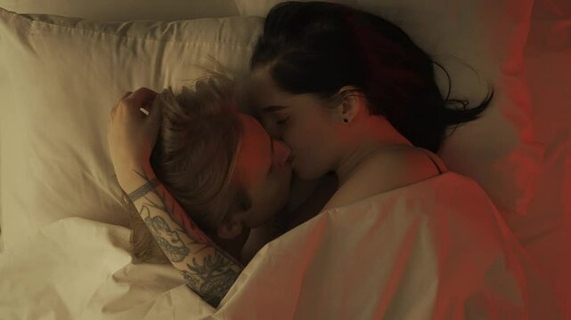 Top view young loving couple romantic time in bedroom. Man and woman half naked sensual lovers laying in bed together, passion, intimacy kissing, foreplay and bonding.