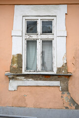 Historic window with peeling paint on a weathered building in an urban setting captures attention in early morning light