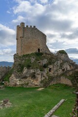 Tower of Homage of the medieval castle in a meadow of green grass at sunset
