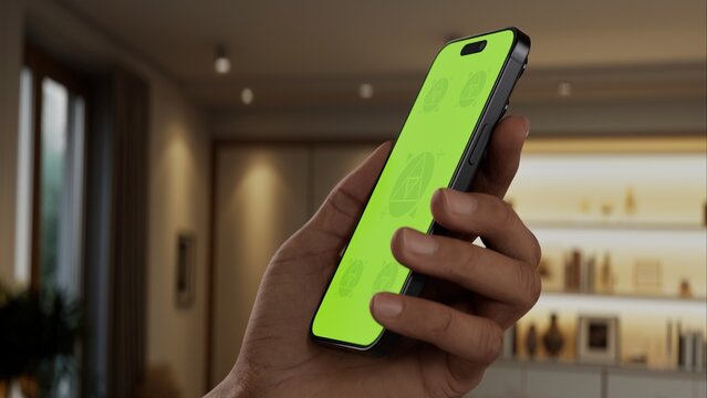 GREEN SCREEN CHROMA KEY A person holds a smartphone in a modern, well-lit living room during the daytime, ideal for apps related to home, lifestyle, or tech