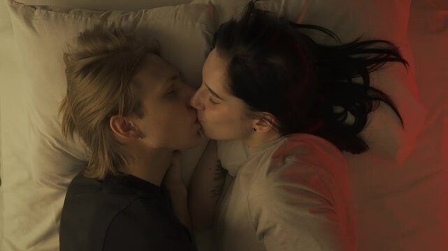 Top view young loving couple romantic time in bedroom. Man and woman half naked sensual lovers laying in bed together, passion, intimacy kissing, foreplay and bonding.