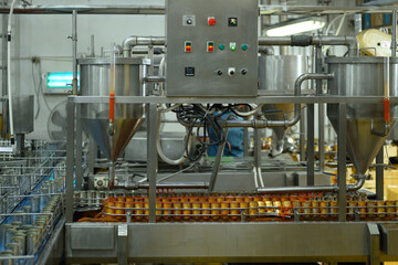 An industrial filling machine pouring sauce into cans at a modern canned fish production facility