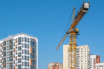 Naklejka premium Equipment for the construction and lifting of bulky goods with construction materials. A tower crane next to new buildings. Construction equipment. Engineering equipment.
