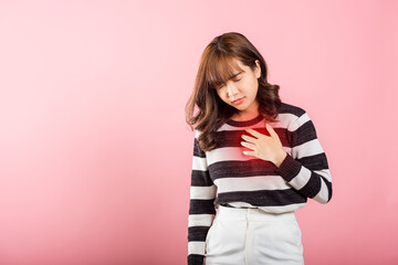 Young woman pressing on chest pain isolated on pink background, painful expression heartache,...