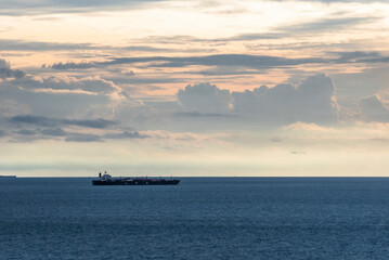 Obraz premium Steel-blue ocean under heavy rain clouds, with silhouettes of cargo ships cutting through the water—silent giants moving steadily beneath a dramatic, stormy sky.