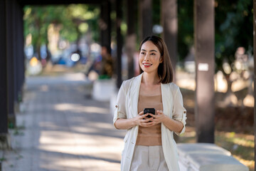 A woman is walking down a sidewalk holding a cell phone