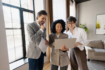 Real estate agents showing property information on laptop to client