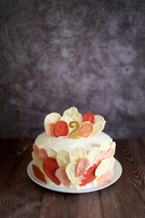 Biscuit birthday cake with decorations stands on a wooden table