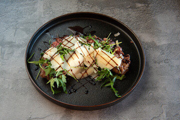 Tagliata di manzo con rucola e grana or sliced ​​beef with rocket and parmesan cheese on grey background