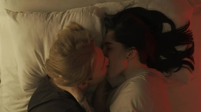 Top view young loving couple romantic time in bedroom. Man and woman half naked sensual lovers laying in bed together, passion, intimacy kissing, foreplay and bonding.