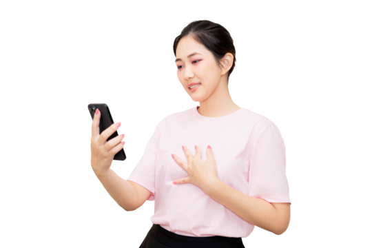 Asian young woman in a pink shirt smiles while holding and looking at her smartphone.